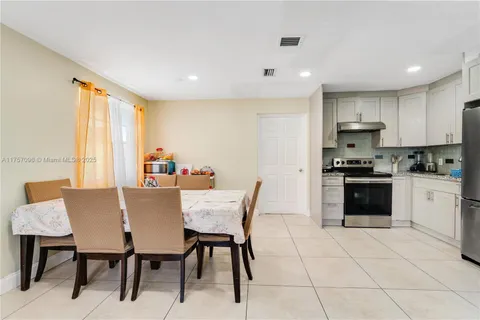 a kitchen with granite countertop a stove a sink a dining table and chairs
