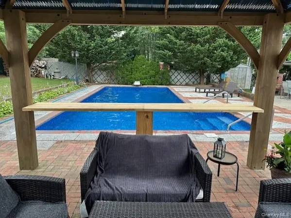 a view of swimming pool with seating area and trees in the background