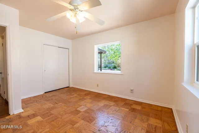 an empty room with a window and a chandelier fan