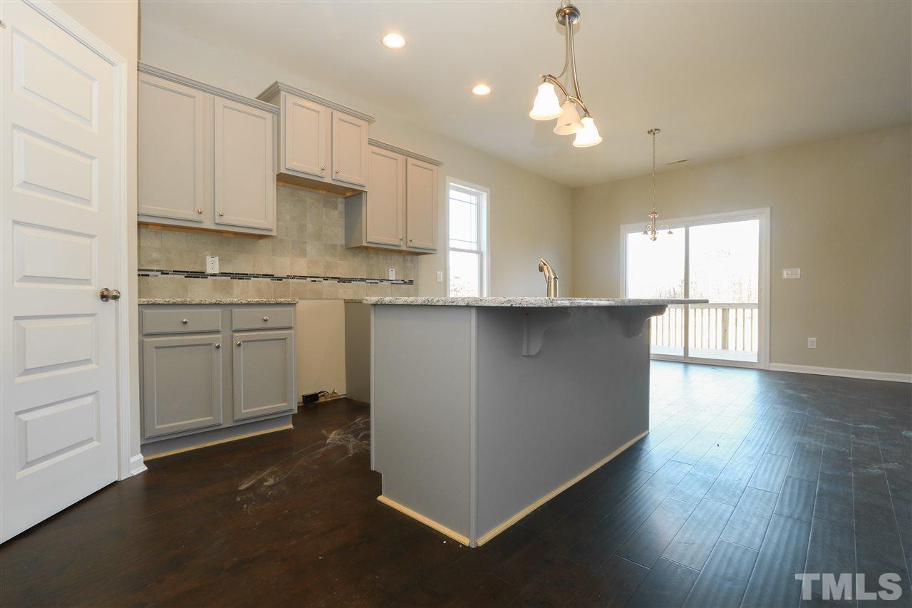1035 2 Claude Road Willow Spring, NC 27592 - Photo 4 of 18 a kitchen with kitchen island a sink dishwasher a stove and white cabinets with wooden floor