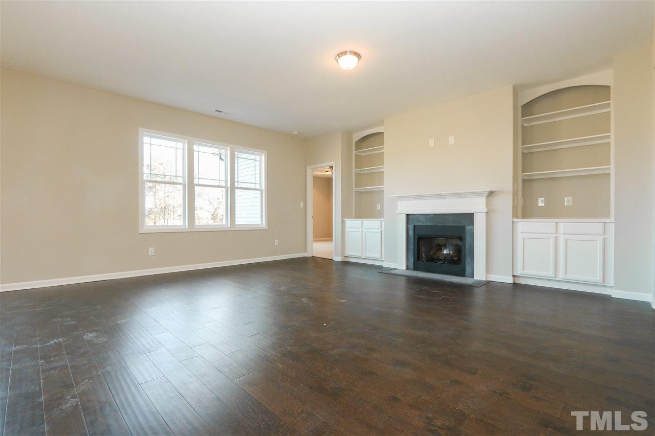 1035 2 Claude Road Willow Spring, NC 27592 - Photo 7 of 18 an empty room with wooden floor fireplace and windows