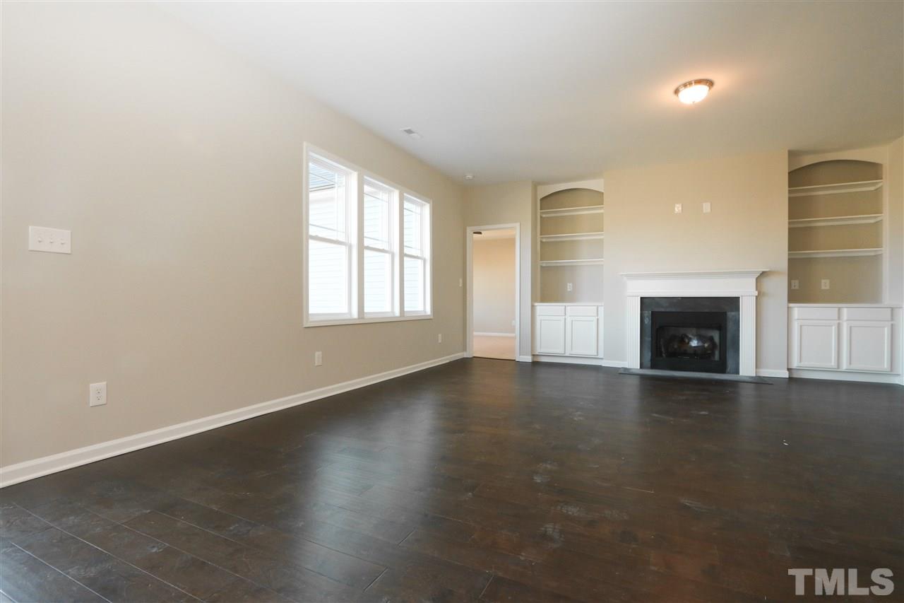 1035 2 Claude Road Willow Spring, NC 27592 - Photo 8 of 18 an empty room with wooden floor and a fireplace
