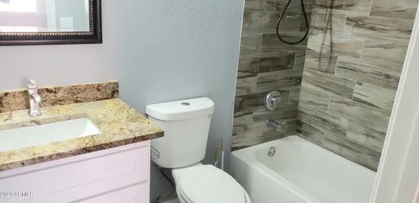 a bathroom with a granite countertop bathtub sink and toilet