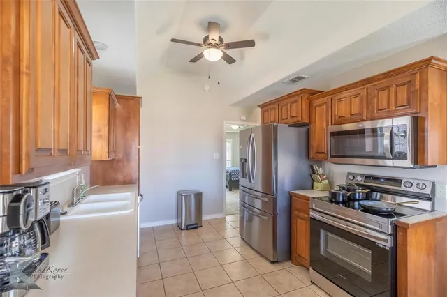 a kitchen with stainless steel appliances granite countertop a refrigerator a stove a sink and a microwave