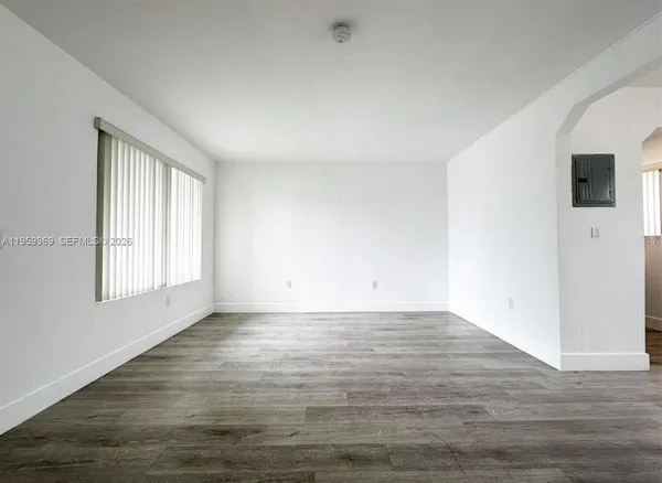 a view of an empty room with wooden floor and a window
