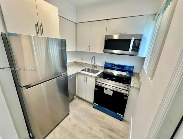 a kitchen with stainless steel appliances a refrigerator a stove a microwave and a sink