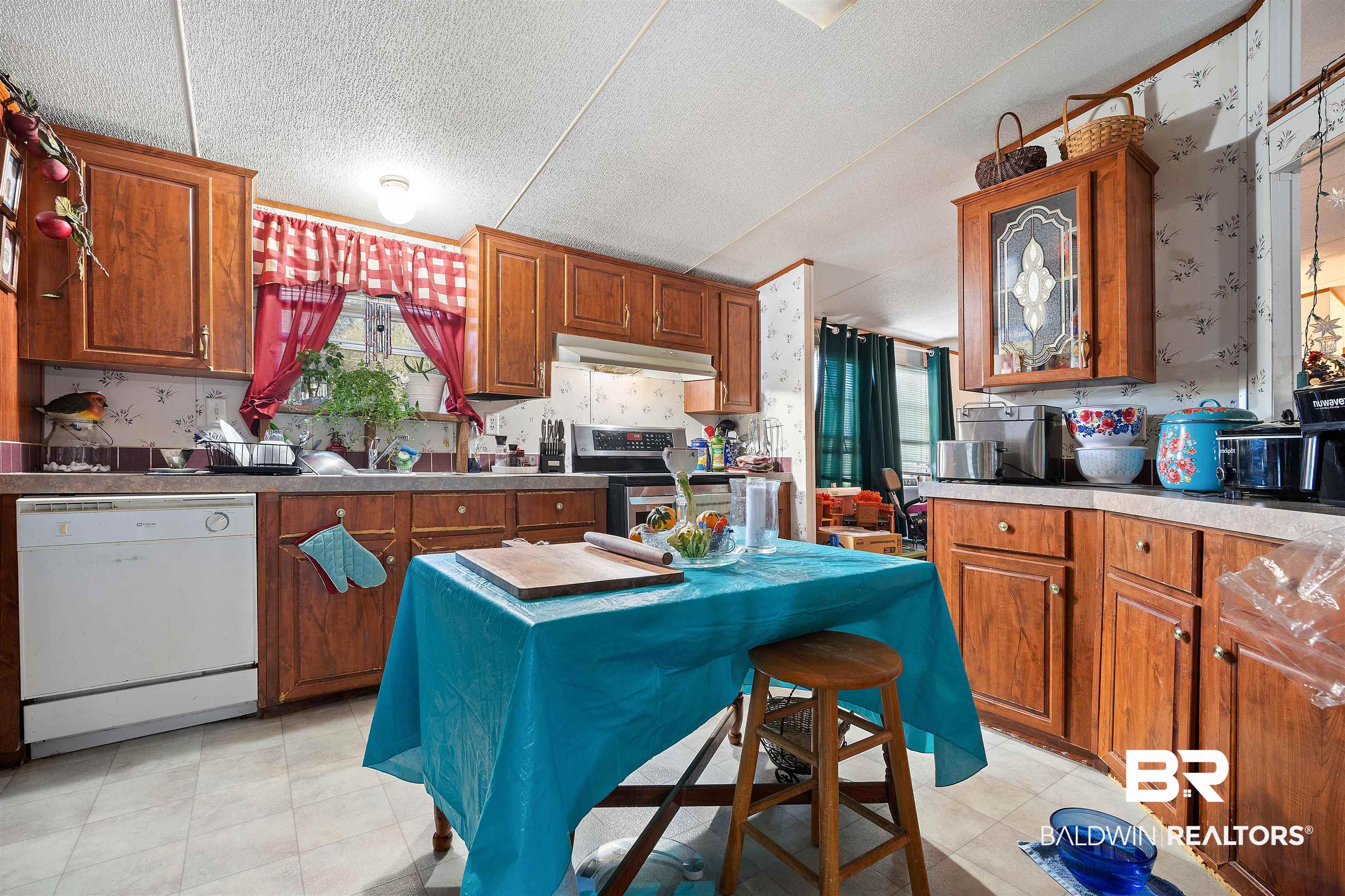 23700 Cumberland Road Robertsdale, AL 36567 - Photo 8 of 33 Kitchen with wallpapered walls, dishwasher, stainless steel electric stove, brown cabinetry, and a textured ceiling