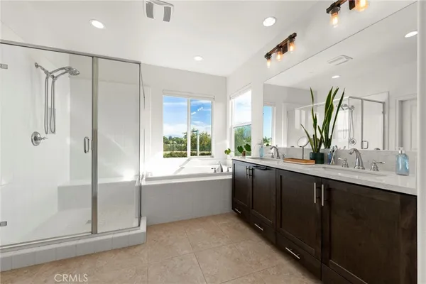 a bathroom with a double vanity sink a large mirror a bathtub and next to a window