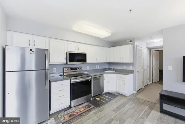 a kitchen with stainless steel appliances granite countertop a refrigerator stove a sink dishwasher and a refrigerator with wooden floor