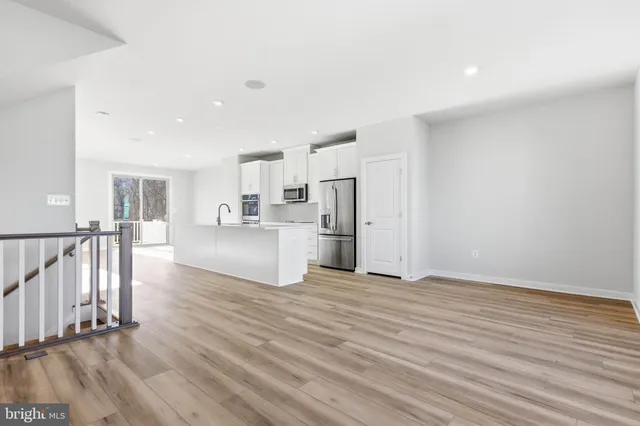 a view of a hallway with wooden floor and a living room