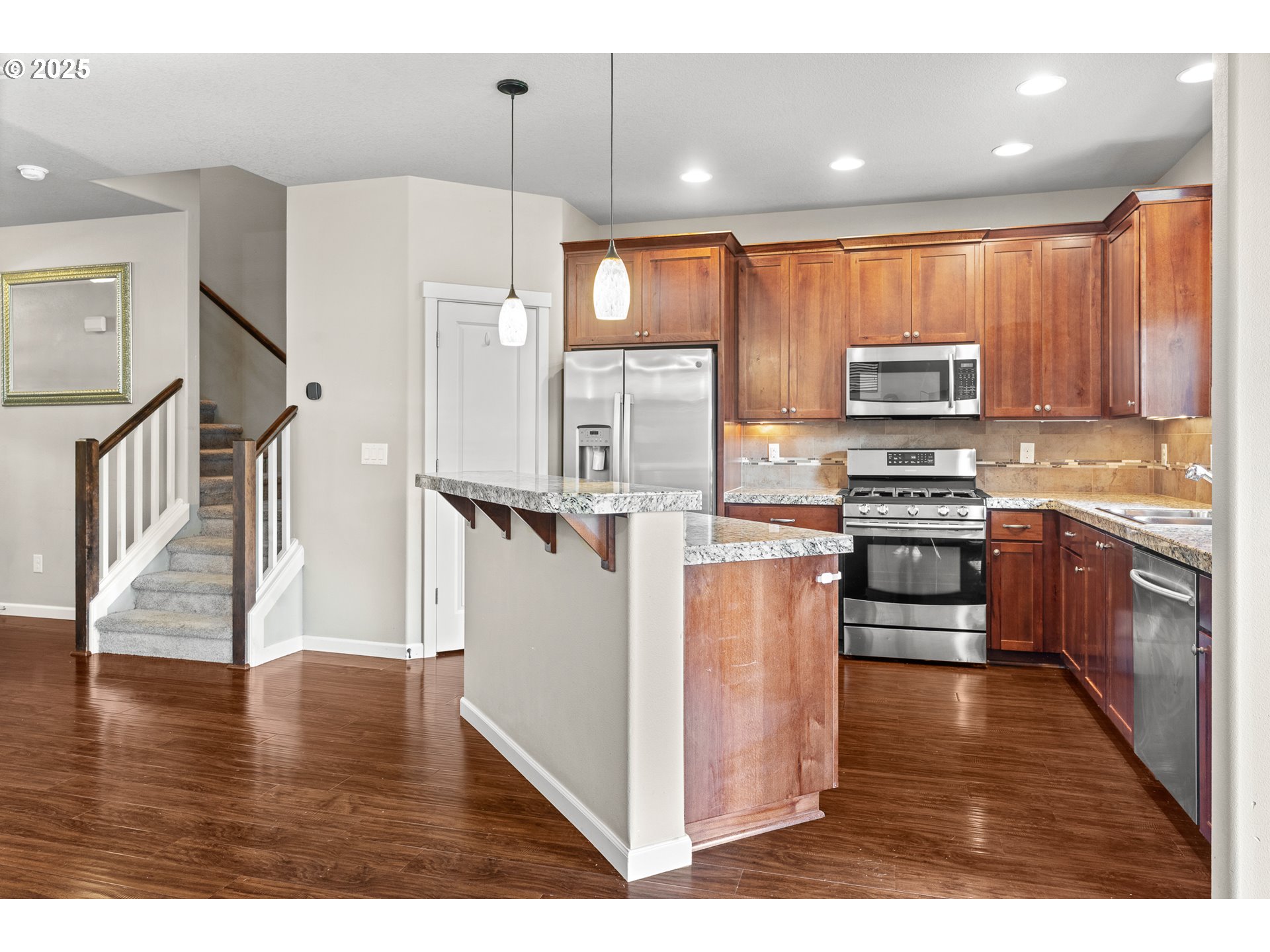 514 North 40th Avenue Ridgefield, WA 98642 - Photo 13 of 46 a kitchen with stainless steel appliances kitchen island wooden cabinets a stove a sink and a wooden floor