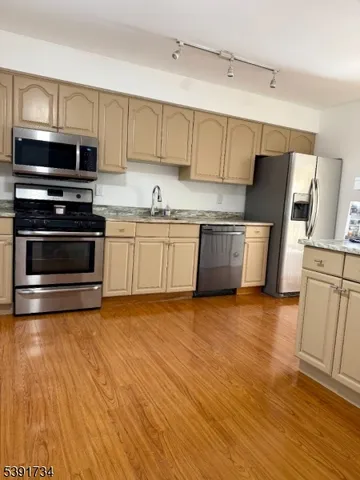 a kitchen with granite countertop a refrigerator stove and wooden floor