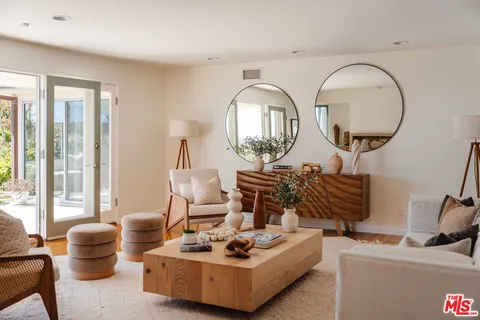 a living room with furniture a mirror and a large window
