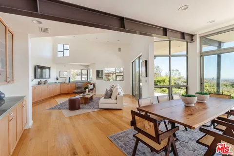 a living room with furniture large window and wooden floor
