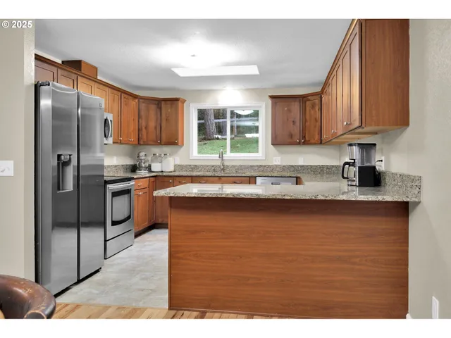 a kitchen with stainless steel appliances granite countertop a refrigerator a sink dishwasher a stove and oven
