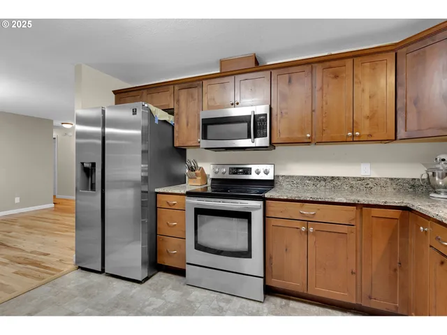 a kitchen with stainless steel appliances granite countertop a refrigerator a stove a sink and dishwasher with wooden floor