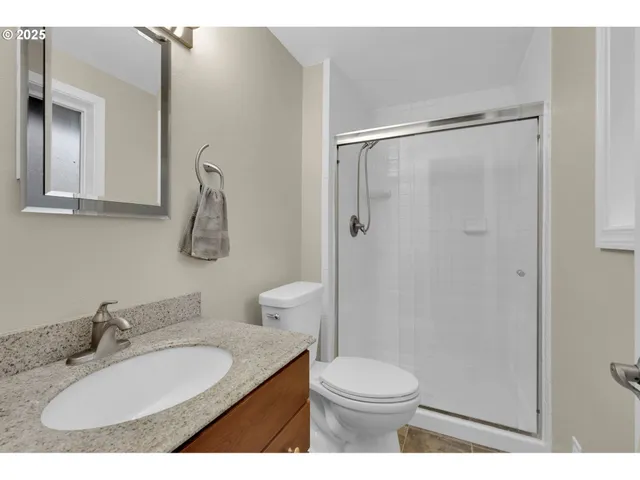 a bathroom with a granite countertop sink toilet a mirror and shower