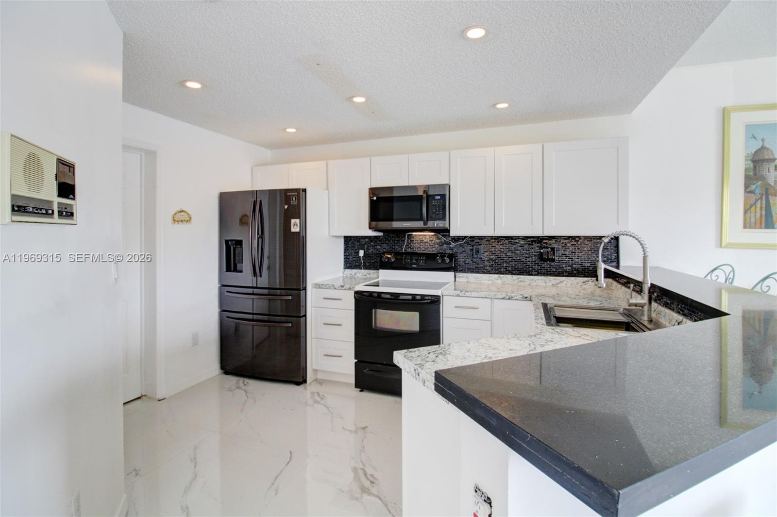 15490 Southwest 47th Street Miami, FL 33185 - Photo 17 of 43 a kitchen with stainless steel appliances granite countertop a refrigerator a stove a sink a microwave oven with white cabinets