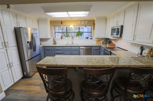 a kitchen with stainless steel appliances granite countertop a sink a stove a refrigerator and cabinets