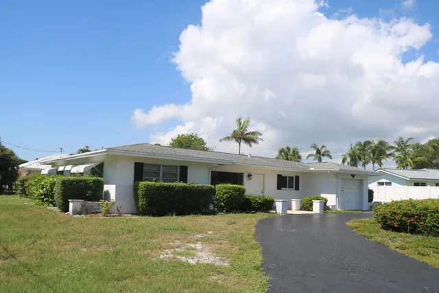 a front view of a house with a yard and potted plants
