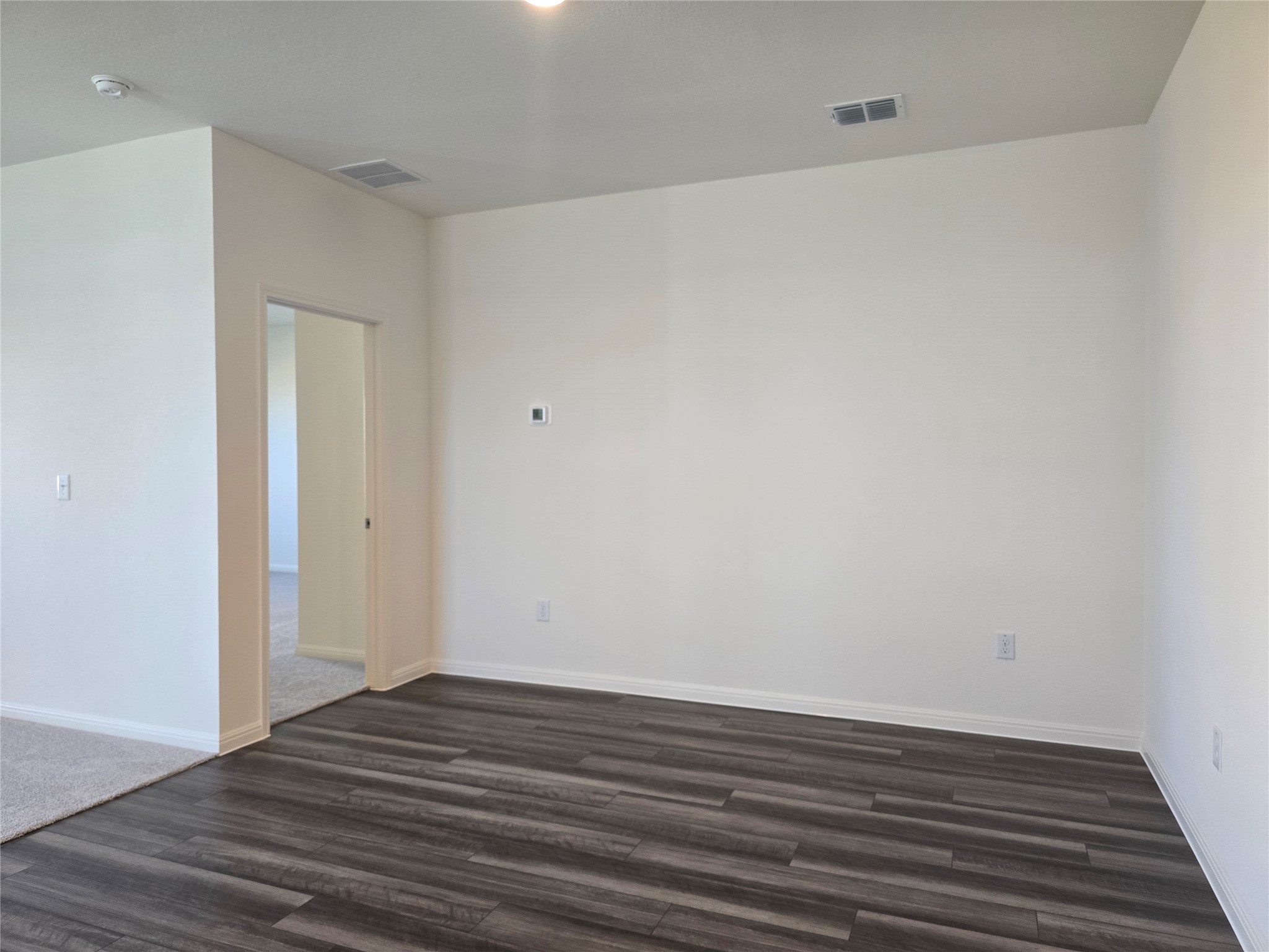 509 McFadin Way Taylor, TX 76574 - Photo 14 of 23 Empty room featuring dark wood-style flooring and baseboards