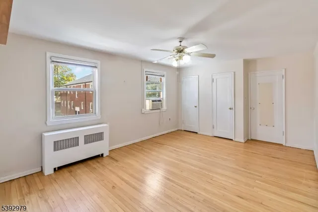 a view of an empty room with a window and wooden floor