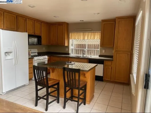a kitchen with stainless steel appliances granite countertop a table chairs sink refrigerator and cabinets