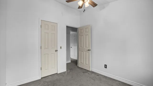 an empty room with a chandelier fan and closet area