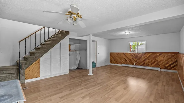 a view of a livingroom with wooden floor stairs and a chandelier