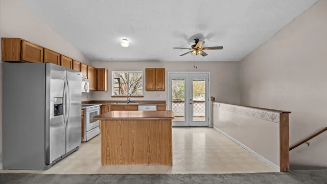 a kitchen with stainless steel appliances granite countertop a refrigerator a stove and a sink