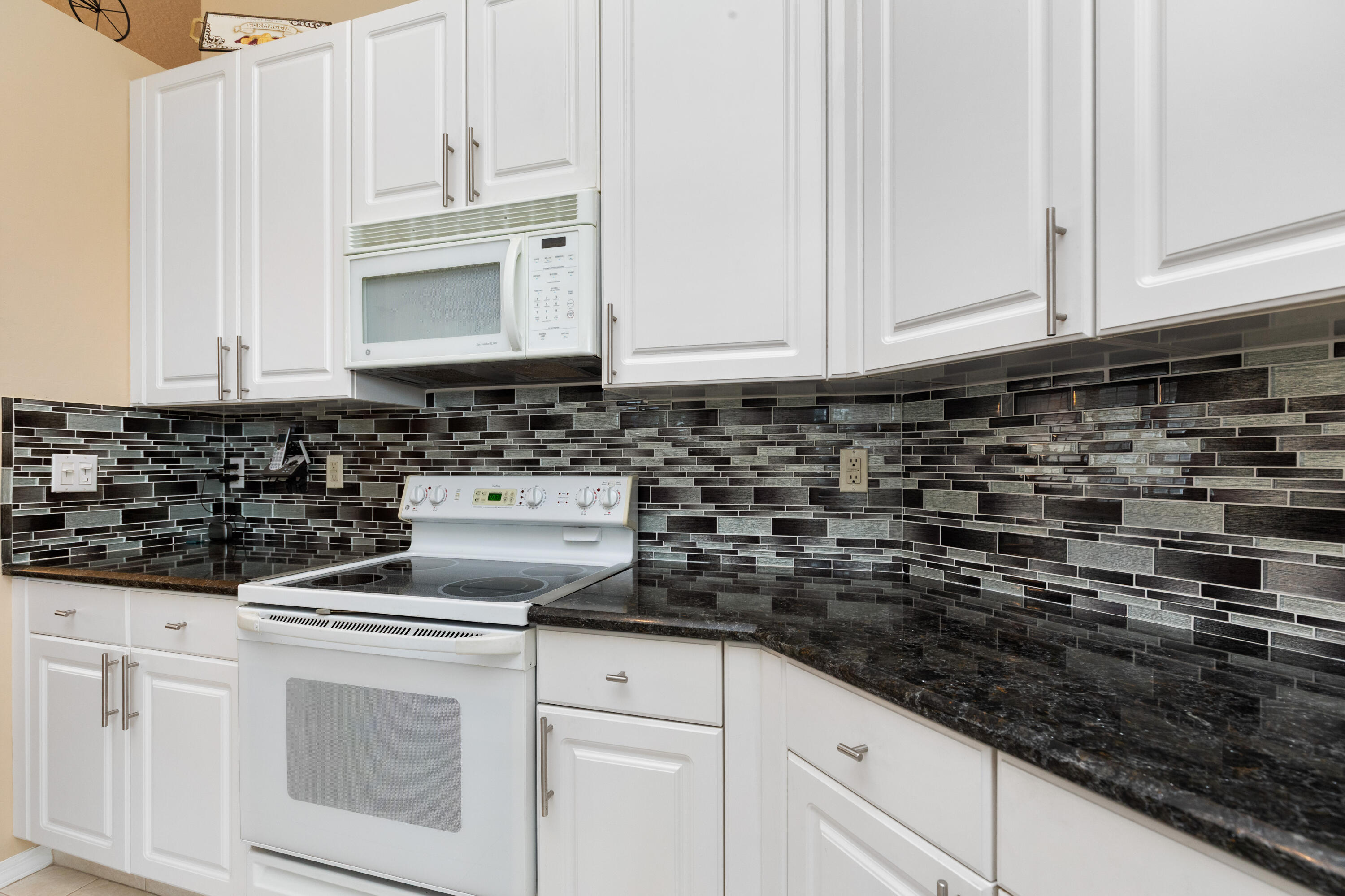 6698 Vía Roma Delray Beach, FL 33446 - Photo 11 of 50 a kitchen with white cabinets and white appliances