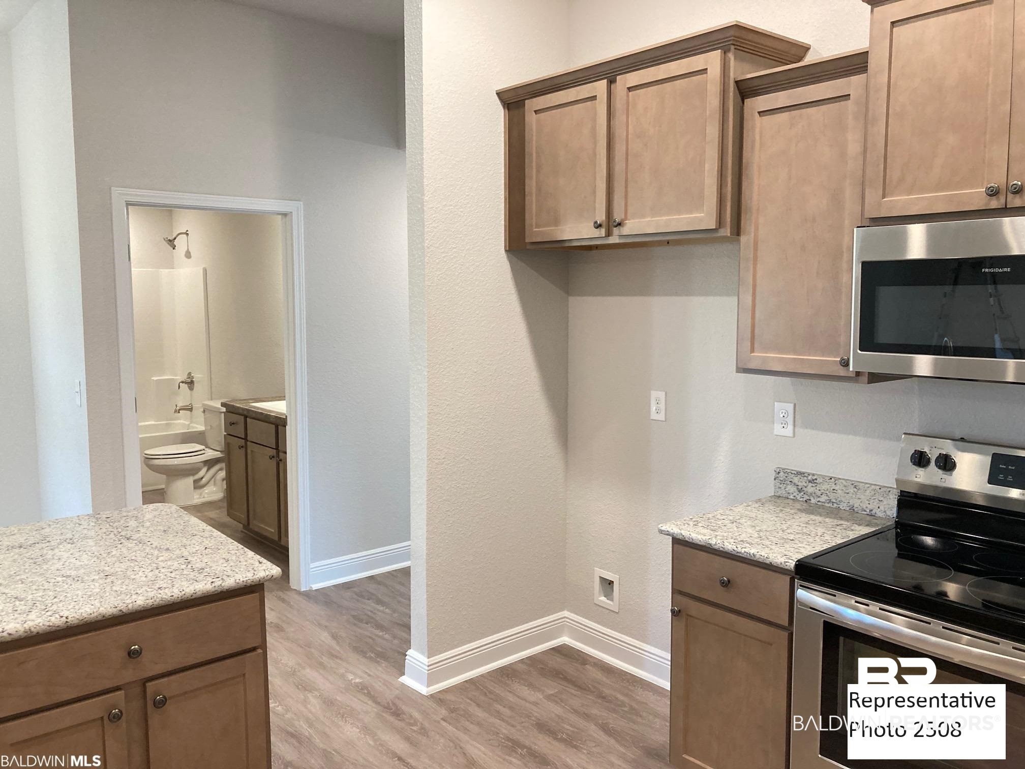 2201 Pollard Road Daphne, AL 36526 - Photo 4 of 15 Kitchen featuring appliances with stainless steel finishes, light wood-type flooring, and light stone counters
