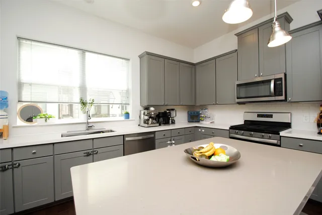 a kitchen with stainless steel appliances a stove a sink and a white cabinets