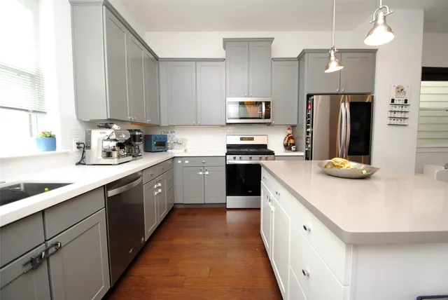 a kitchen with stainless steel appliances a sink a stove top oven a refrigerator a sink and dishwasher with wooden floor