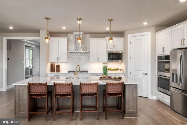 a kitchen with stainless steel appliances kitchen island granite countertop a table chairs and a refrigerator