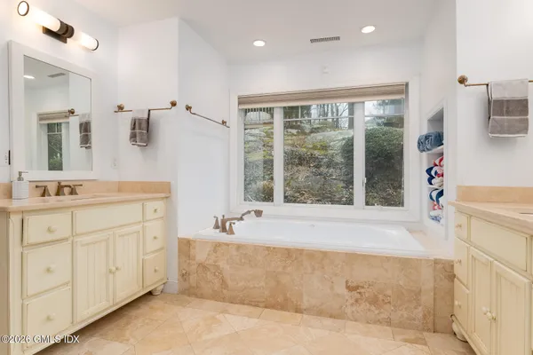 a spacious bathroom with a tub sink and mirror