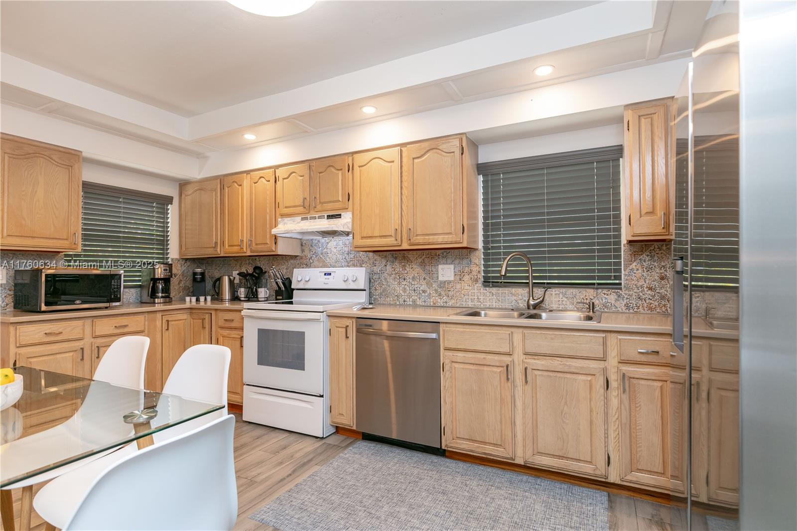 128 Southwest 5th Street Hallandale Beach, FL 33009 - Photo 12 of 17 a kitchen with white cabinets sink and window