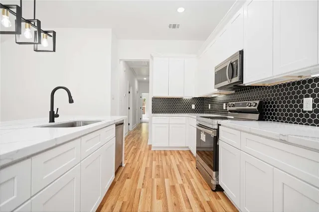 a kitchen with a sink dishwasher a stove and a microwave oven with cabinets