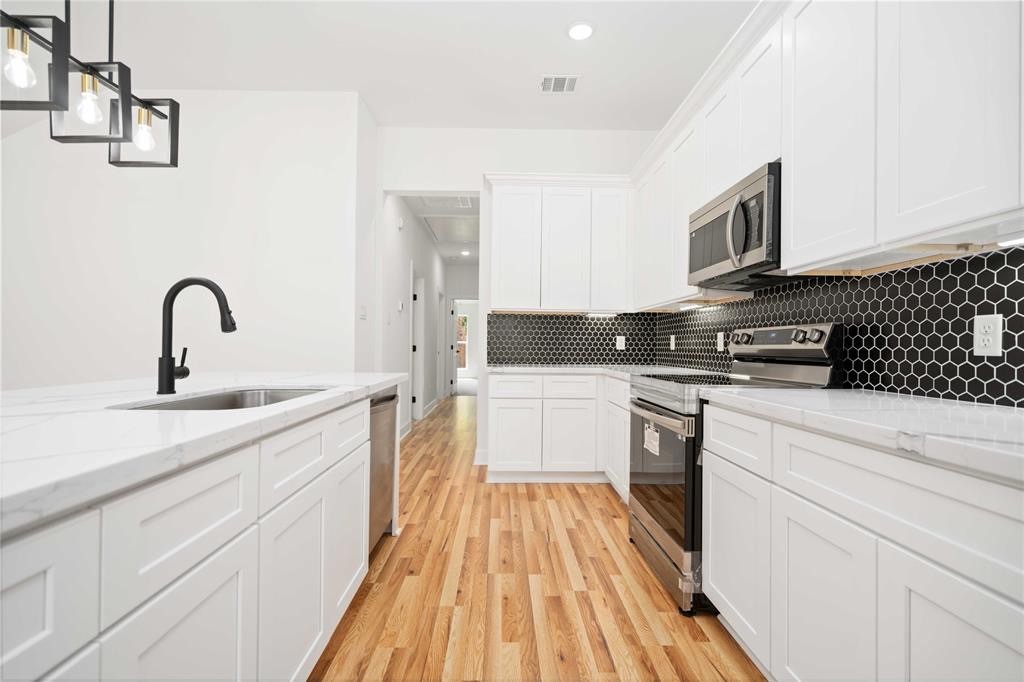 205 Bolden Street, Unit B Houston, TX 77029 - Photo 3 of 15 a kitchen with a sink dishwasher a stove and a microwave oven with cabinets