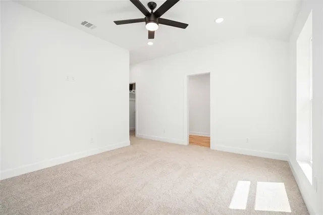 an empty room with a ceiling fan and carpet