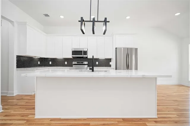 a view of kitchen with stainless steel appliances cabinets and wooden floor