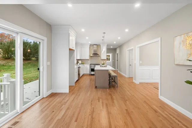 a view of a kitchen with kitchen island wooden floors and stainless steel appliances