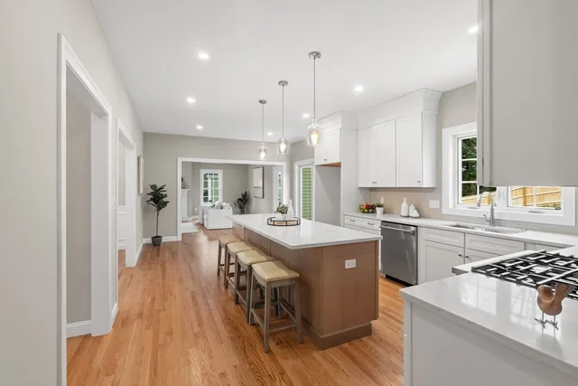 a kitchen with stainless steel appliances a stove a sink dishwasher and a refrigerator with wooden floor