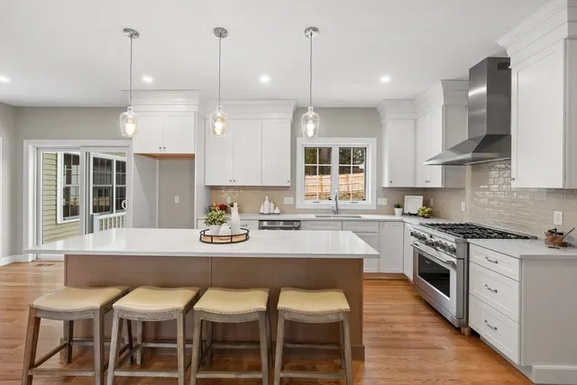 a kitchen with a dining table chairs stove and white cabinets