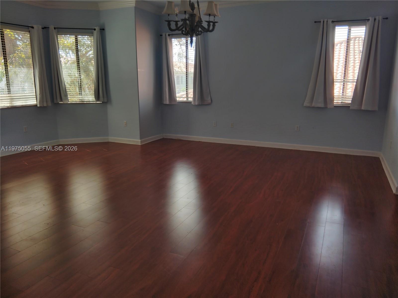 7944 Southwest 194th Street Cutler Bay, FL 33157 - Photo 7 of 10 an empty room with wooden floor and windows