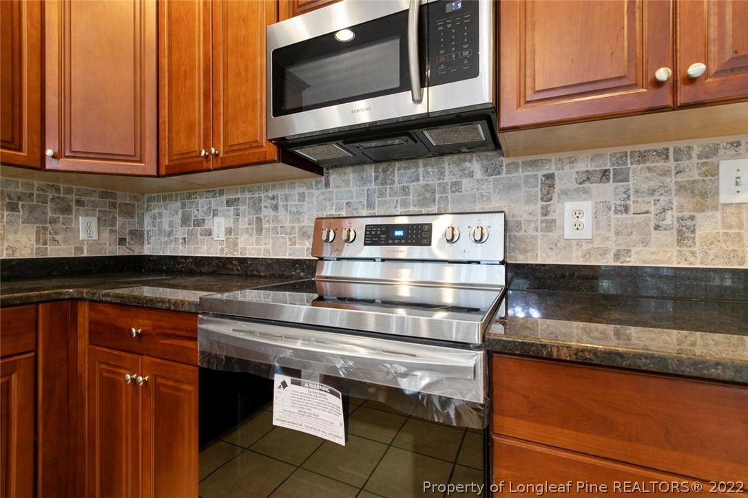 480 Whispering Pines Drive Spring Lake, NC 28390 - Photo 18 of 48 a kitchen with stainless steel appliances granite countertop wooden cabinets a stove and a microwave oven
