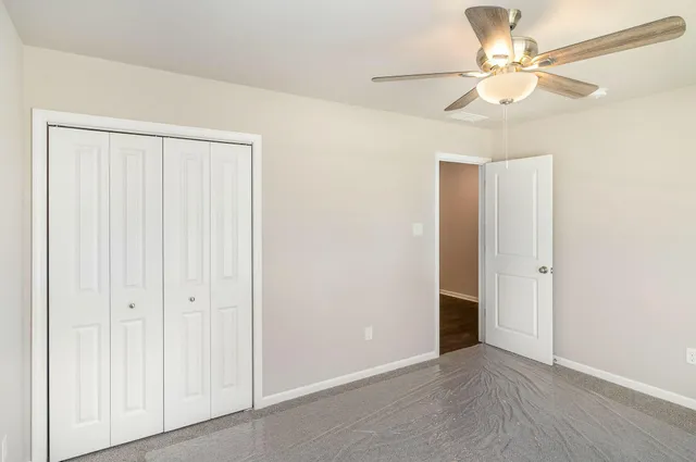 an empty room with windows and fan