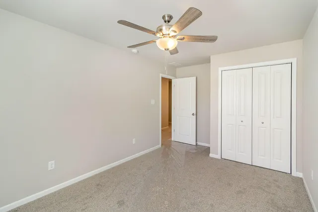 an empty room with closet and a chandelier fan
