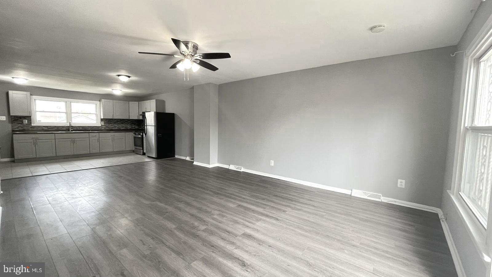 1340 West 7th Street Chester, PA 19013 - Photo 4 of 26 an empty room with wooden floor a ceiling fan and windows