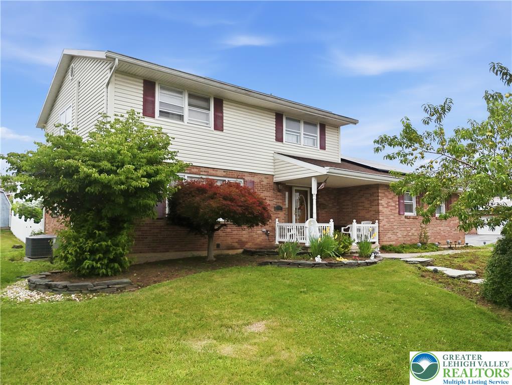 A classic two-story residence with a welcoming covered front porch, featuring tidy landscaping and brick accents.